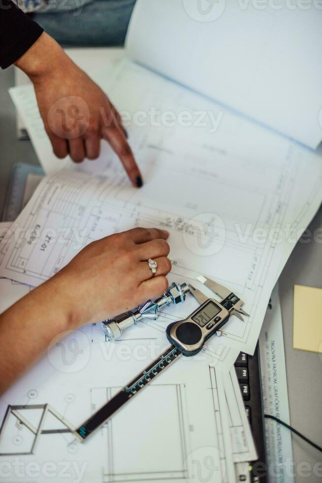 Engineer technician designing drawings mechanical parts engineering Enginemanufacturing factory Industry Industrial work project blueprints measuring bearings caliper tools photo