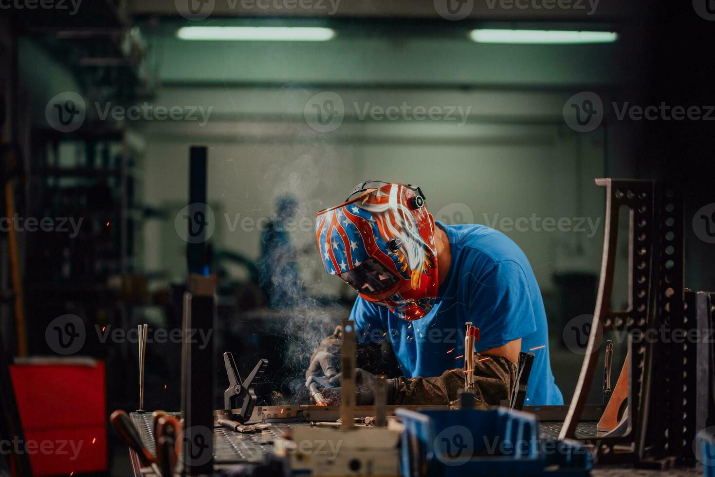 soldador profesional de la industria pesada que trabaja dentro de la fábrica, usa casco y comienza a soldar. enfoque selectivo foto