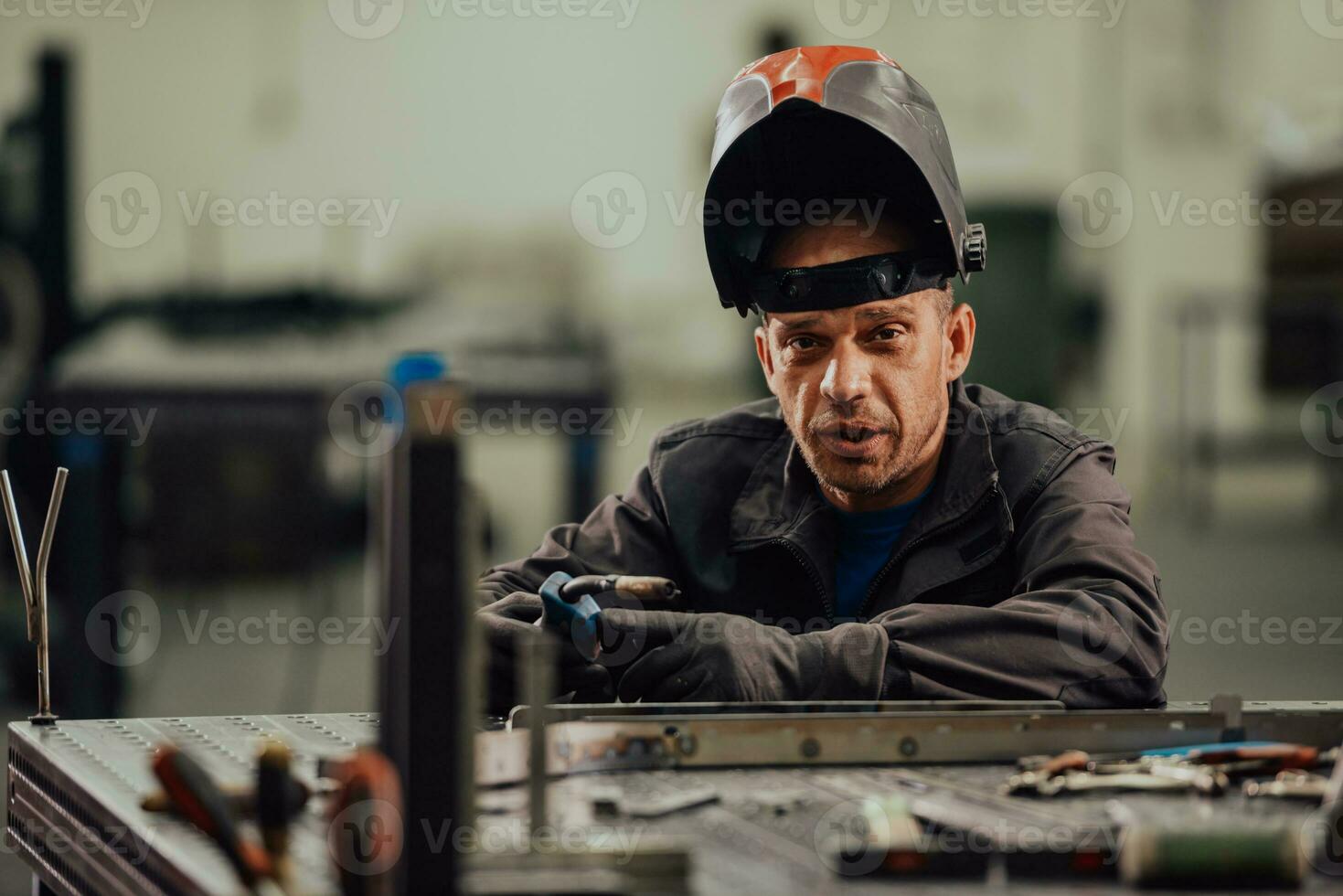 Professional Heavy Industry Welder Working Inside factory, Wears Helmet and Starts Welding. Selective Focus photo