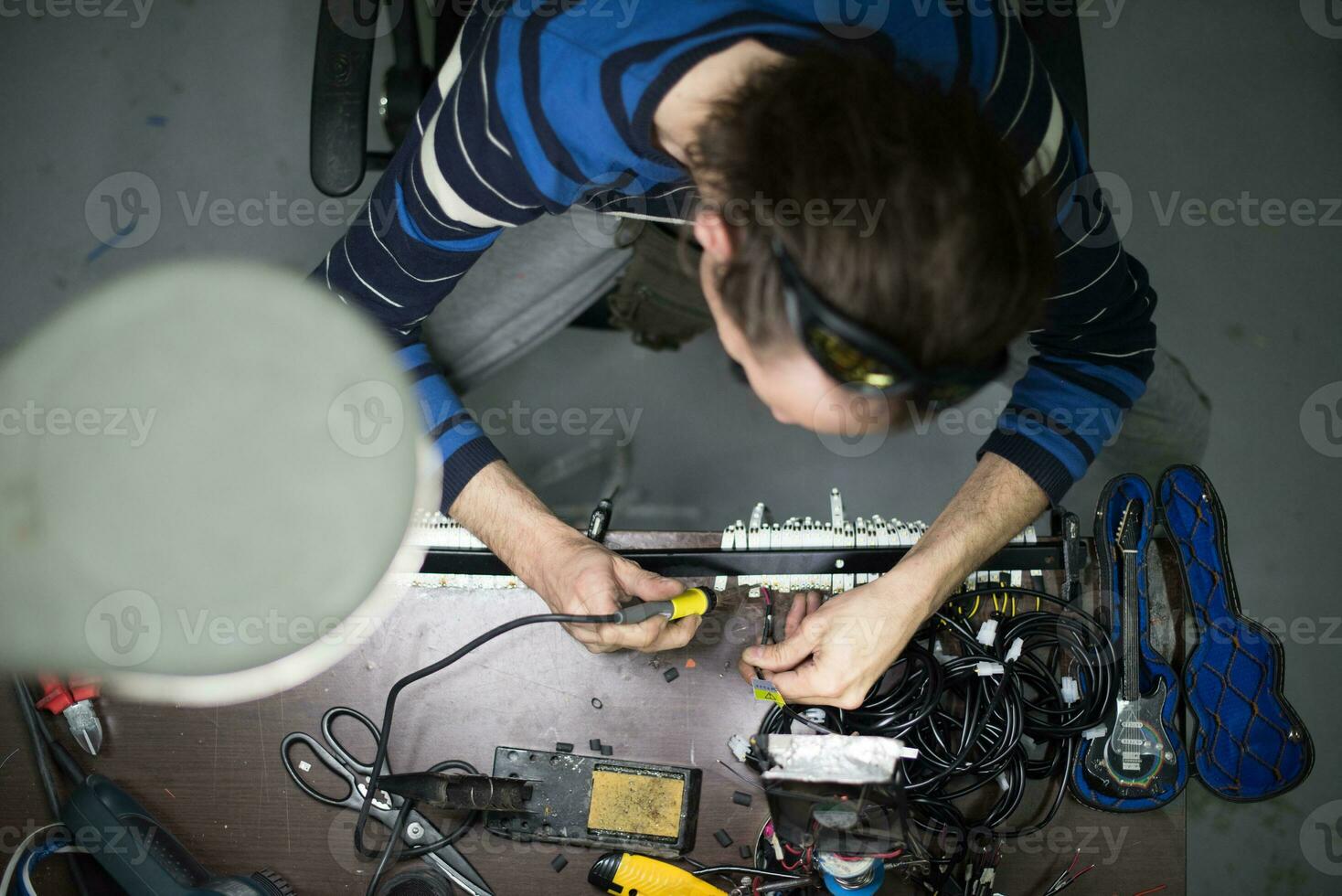 Industrial worker man soldering cables of manufacturing equipment in a factory. Selective focus photo