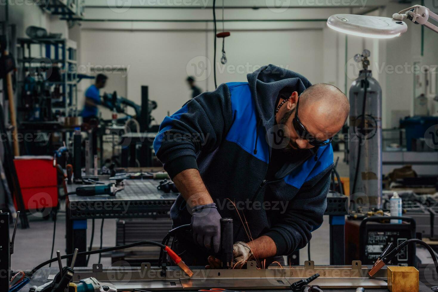Industrial worker man soldering cables of manufacturing equipment in a factory. Selective focus photo