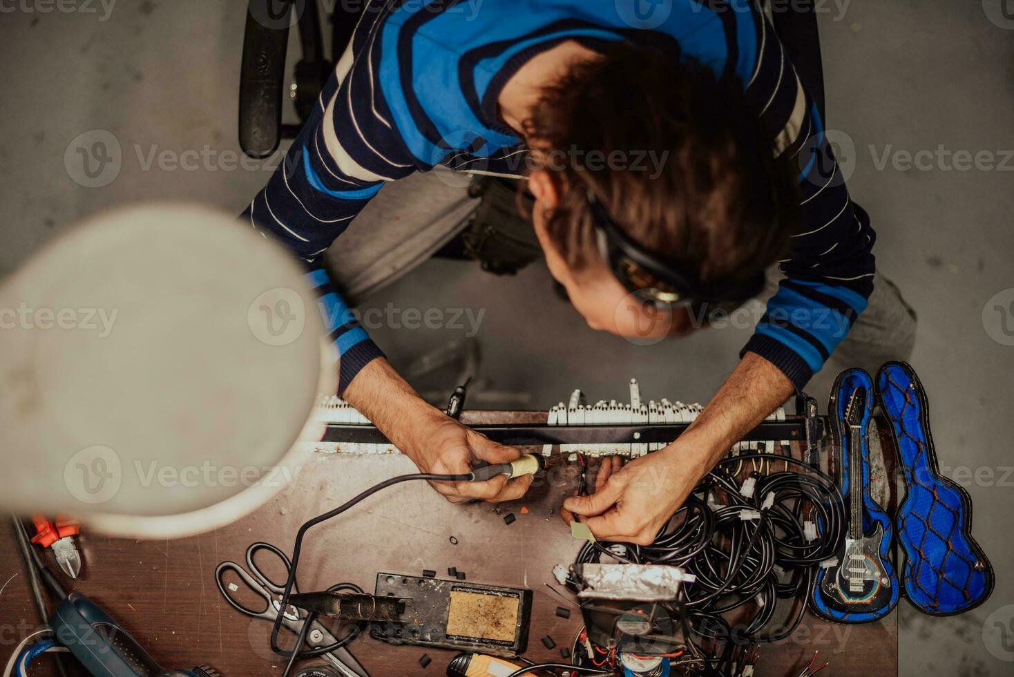 Industrial worker man soldering cables of manufacturing equipment in a factory. Selective focus photo