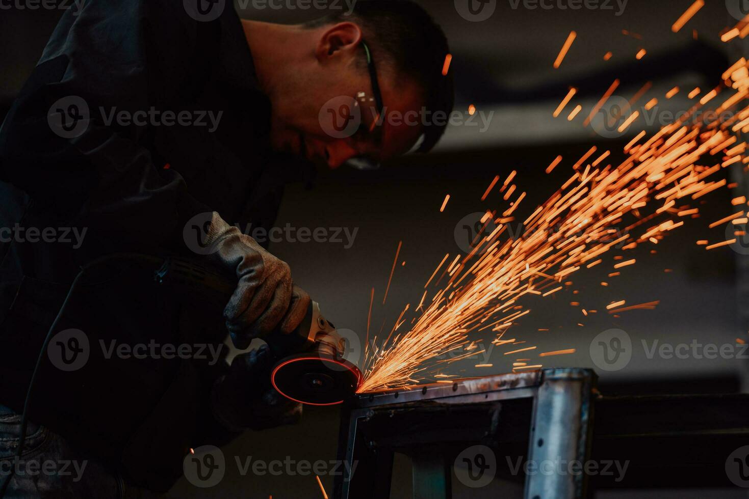 Heavy Industry Engineering Factory Interior with Industrial Worker Using Angle Grinder and Cutting a Metal Tube. Contractor in Safety Uniform and Hard Hat Manufacturing Metal Structures. photo