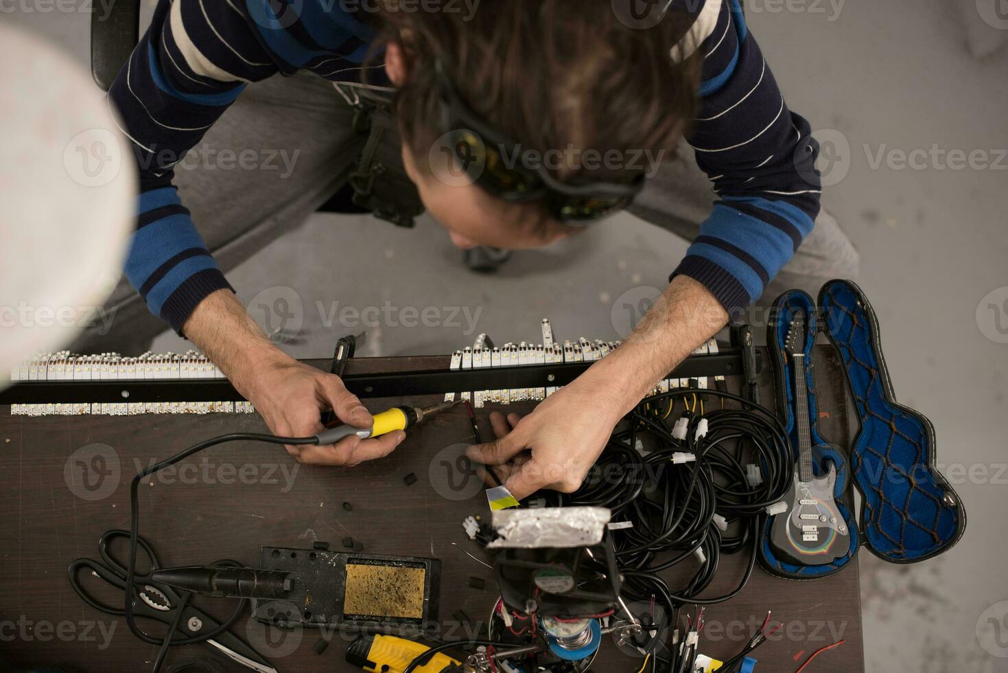 Industrial worker man soldering cables of manufacturing equipment in a factory. Selective focus photo