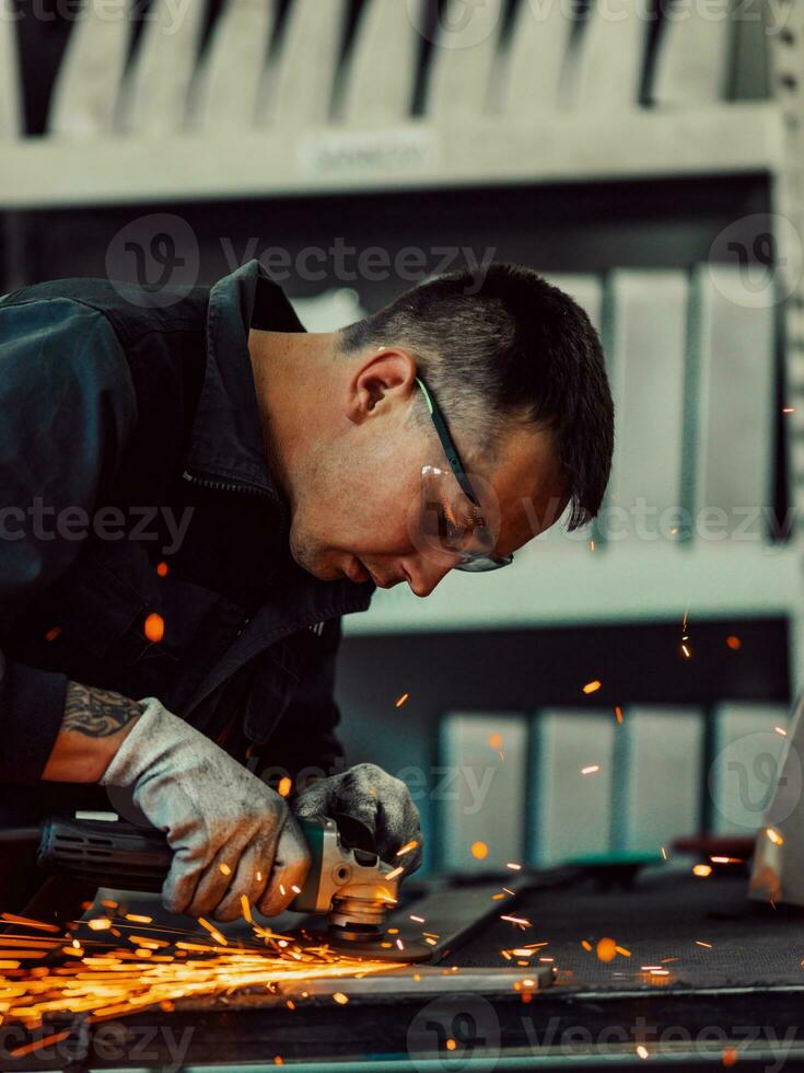 Heavy Industry Engineering Factory Interior with Industrial Worker Using Angle Grinder and Cutting a Metal Tube. Contractor in Safety Uniform and Hard Hat Manufacturing Metal Structures. photo