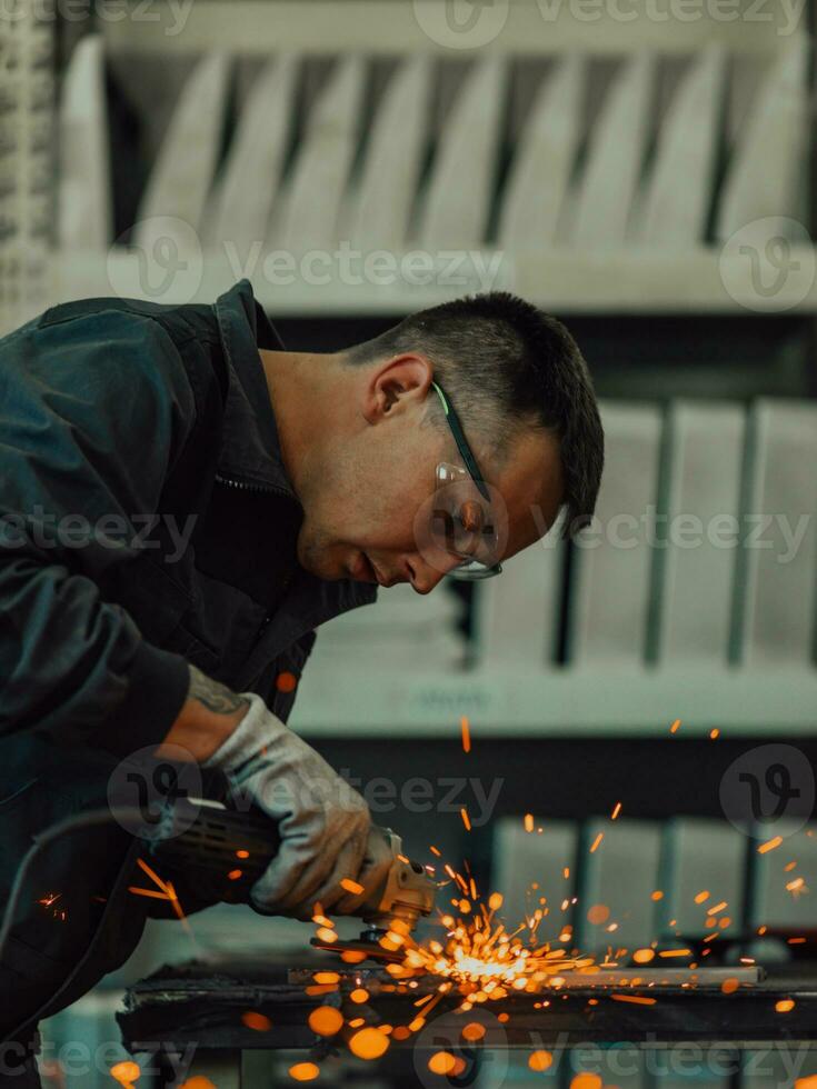 interior de fábrica de ingeniería de industria pesada con trabajador industrial usando amoladora angular y cortando un tubo de metal. contratista en estructuras metálicas de fabricación de cascos y uniformes de seguridad. foto