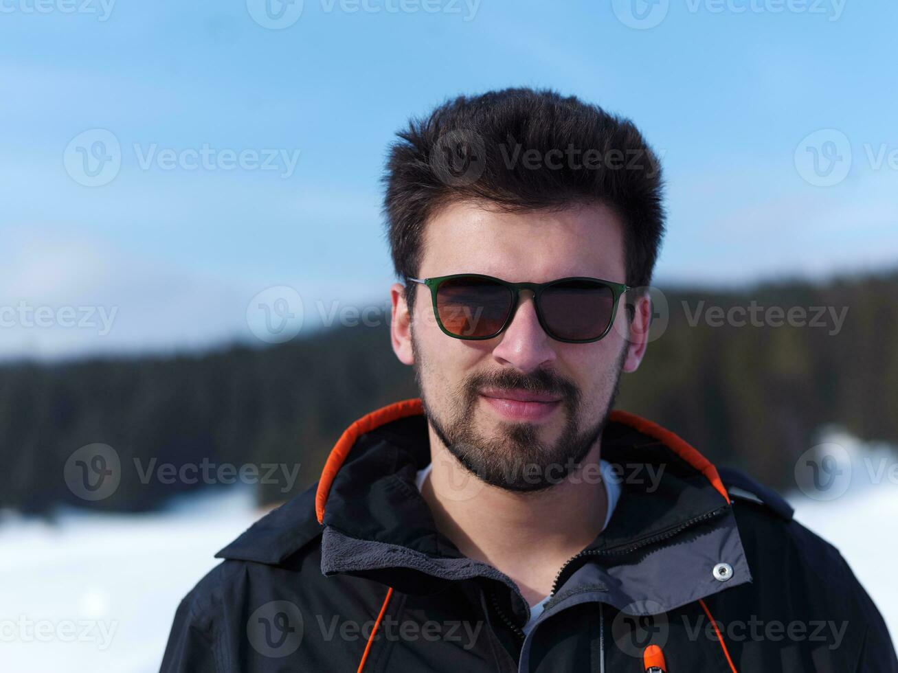 portrait of young man with beard and sunglasses on fresh snow photo