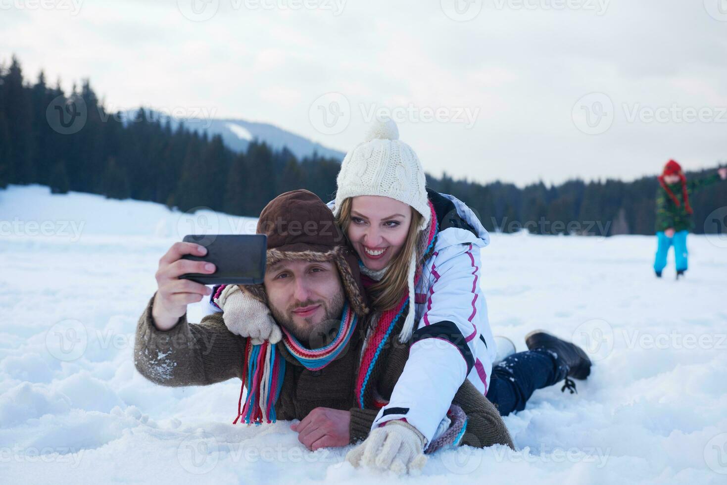 pareja romántica divertirse en la nieve fresca y tomar selfie foto