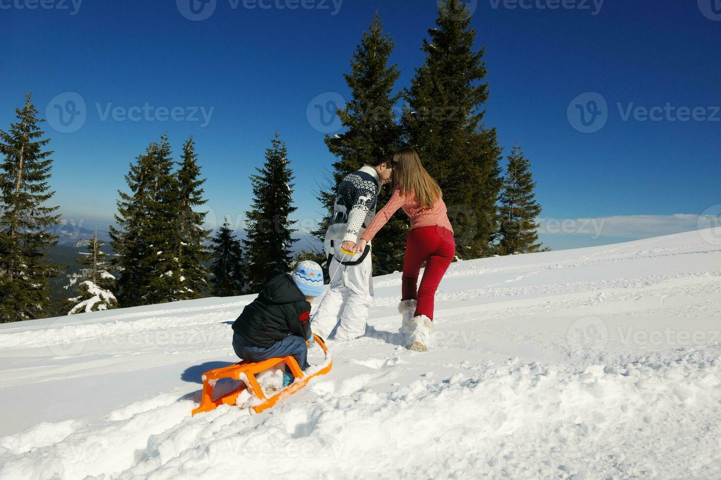 family having fun on fresh snow at winter vacation photo