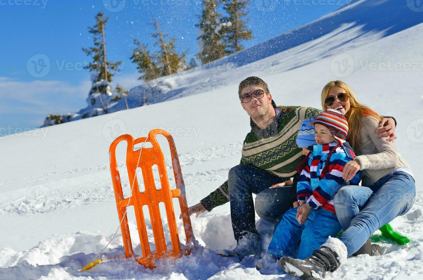 family having fun on fresh snow at winter vacation photo