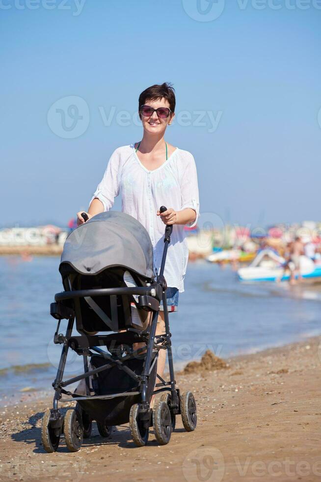 mother walking on beach and push baby carriage photo