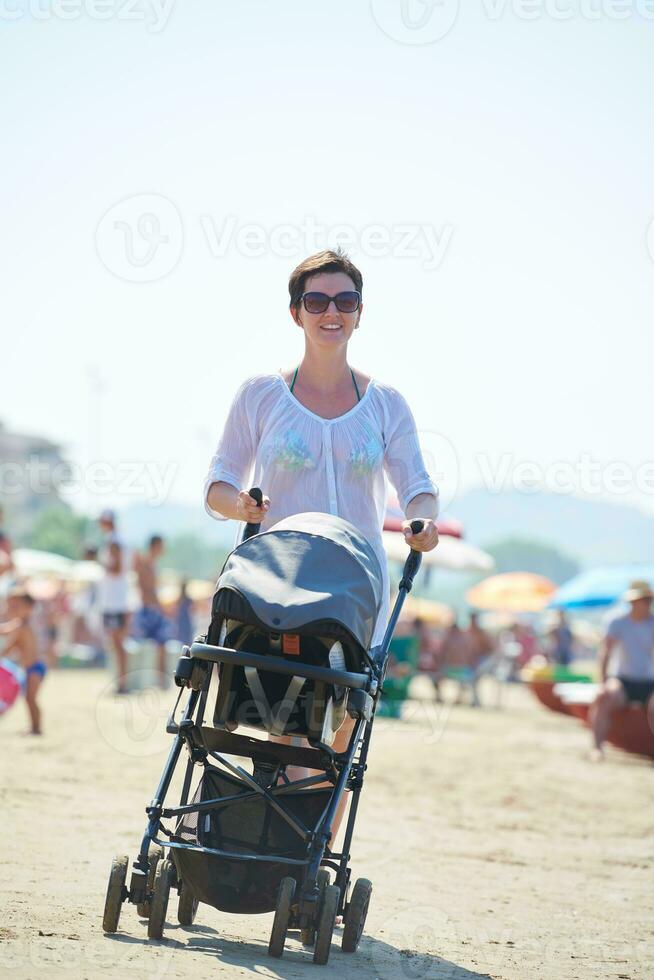 mother walking on beach and push baby carriage photo