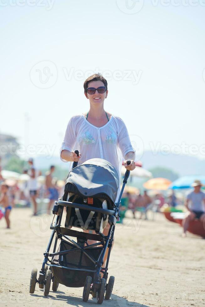 mother walking on beach and push baby carriage photo