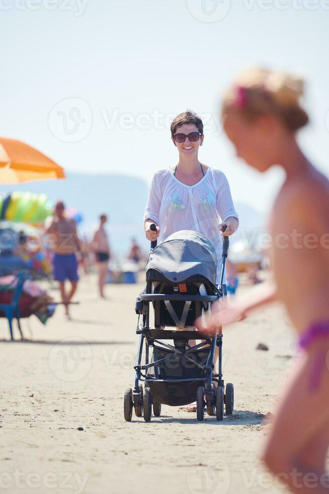 mother walking on beach and push baby carriage photo