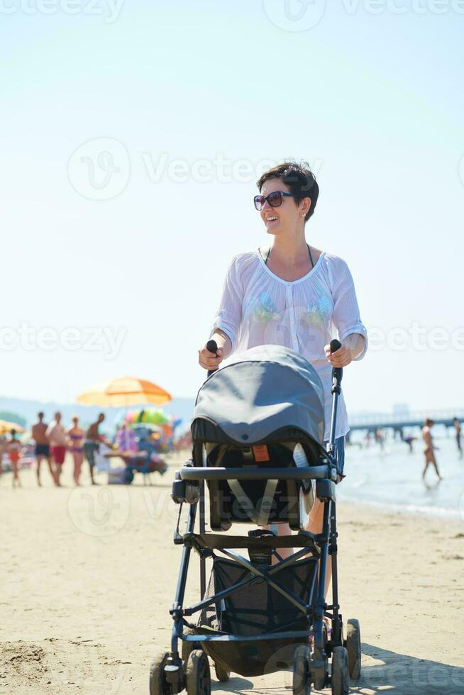 mother walking on beach and push baby carriage photo