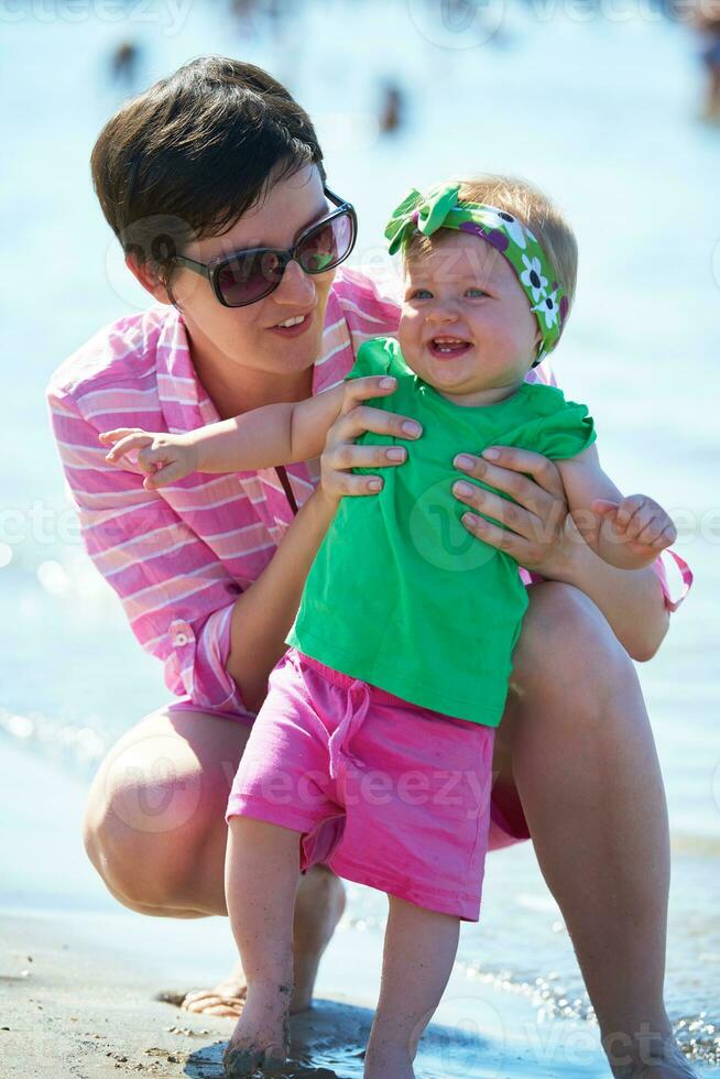 mamá y bebé en la playa se divierten foto