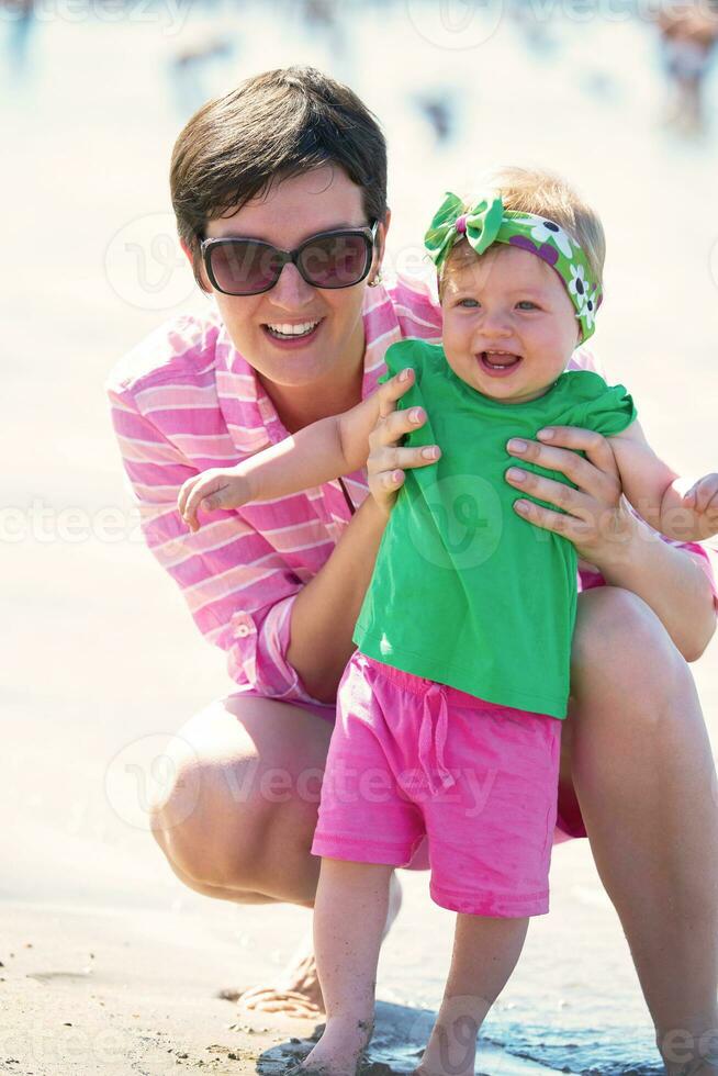 mamá y bebé en la playa se divierten foto