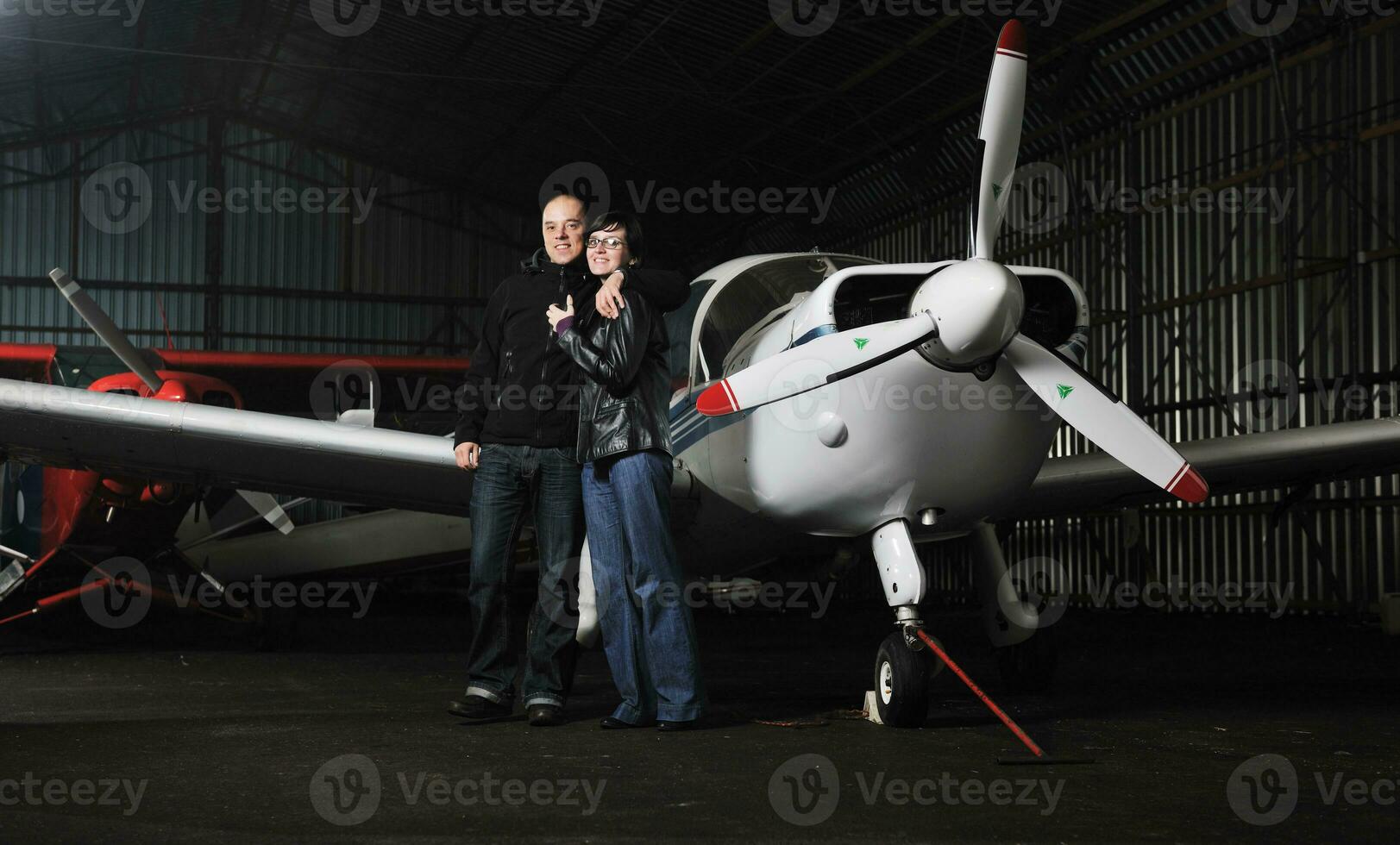 happy young couple posing in front of private airplane photo