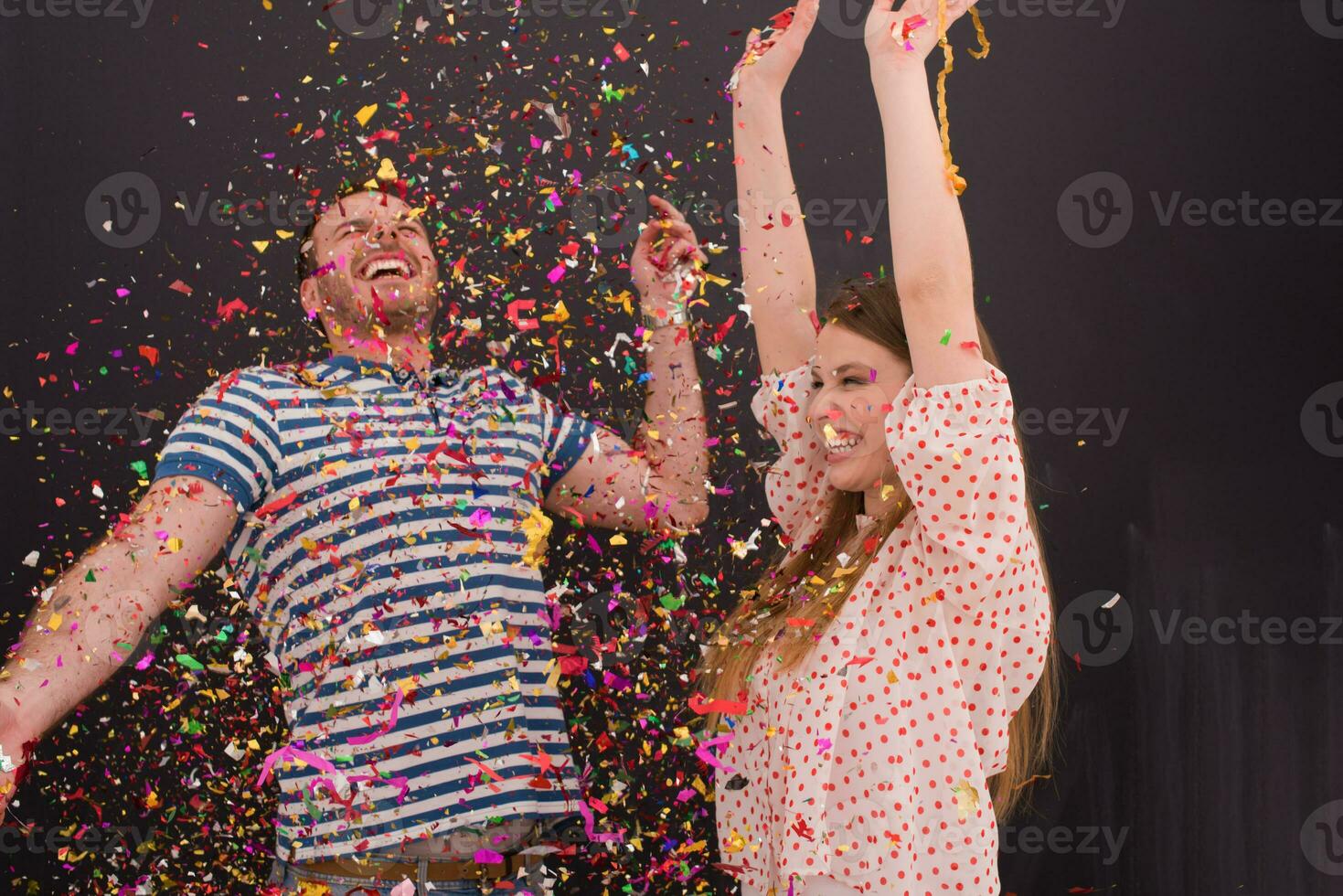 couple blowing confetti in the air isolated over gray photo
