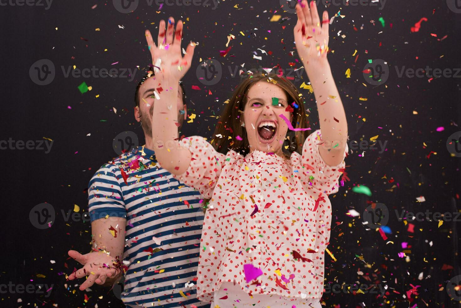 couple blowing confetti in the air isolated over gray photo