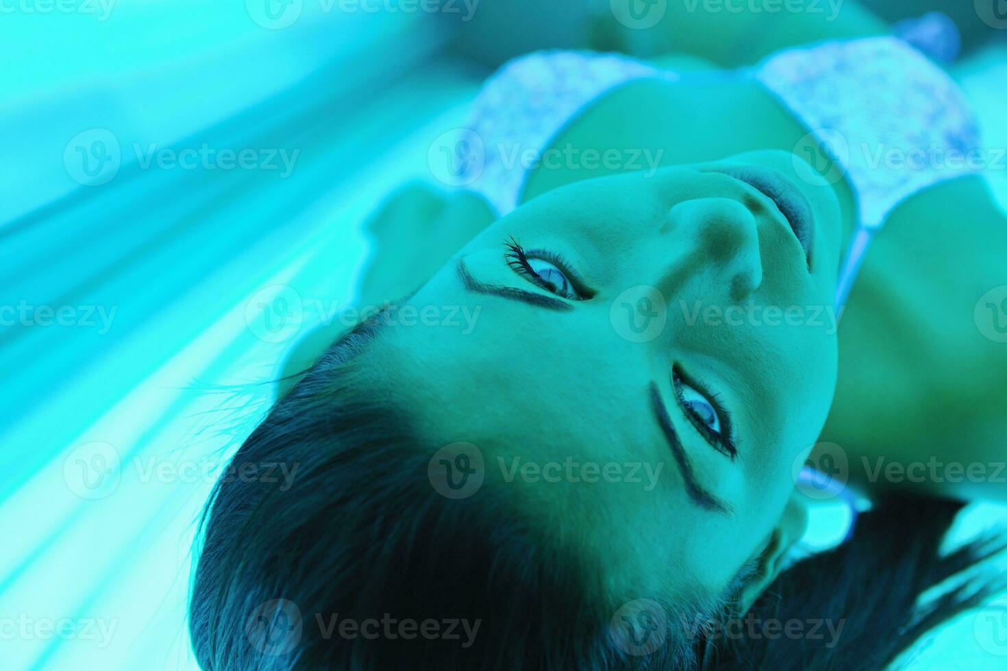Beautiful young woman tanning in solarium photo