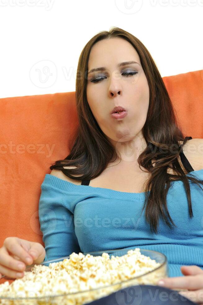 mujer joven come palomitas de maíz y ve la televisión foto