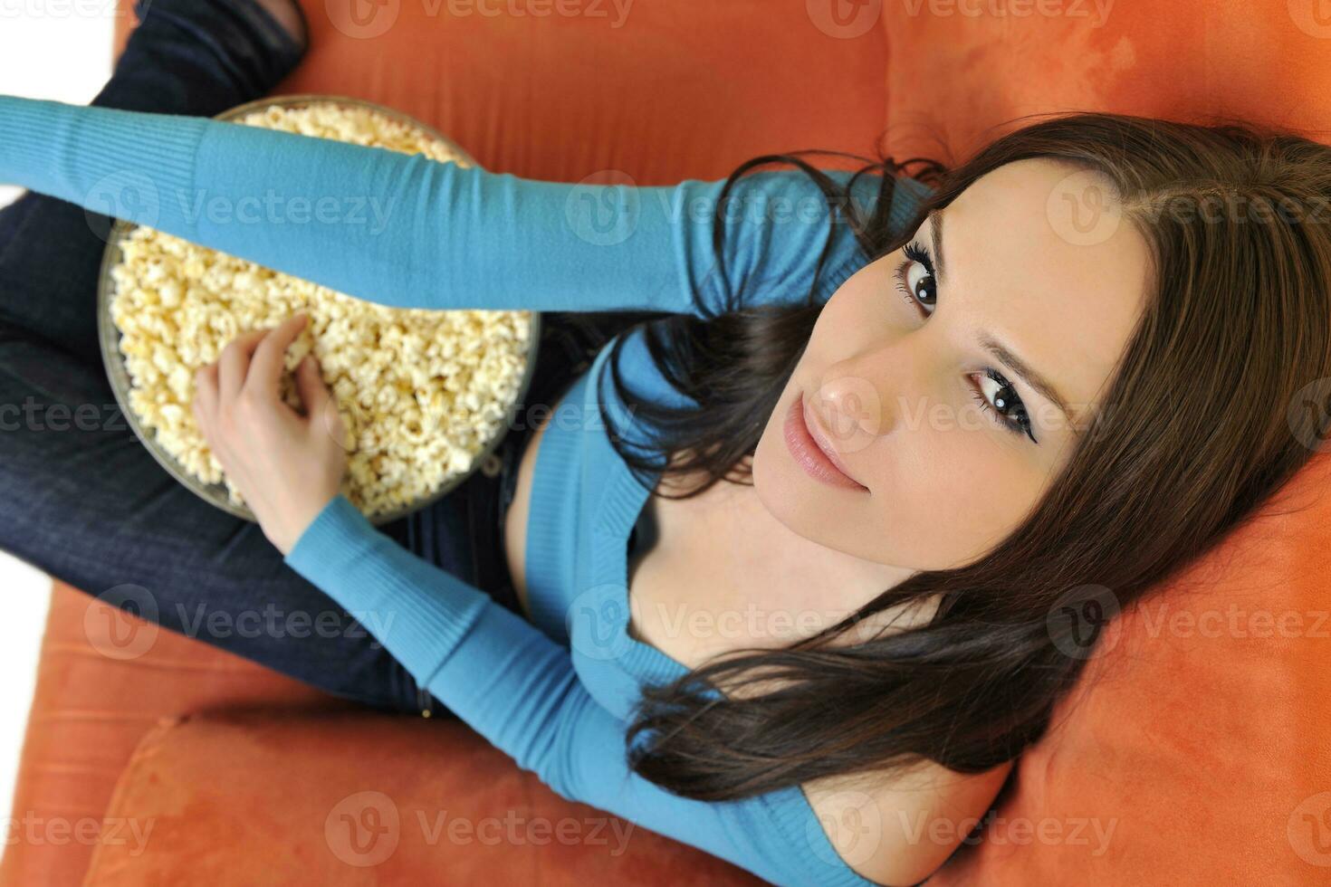 young woman eat popcorn and watching tv photo