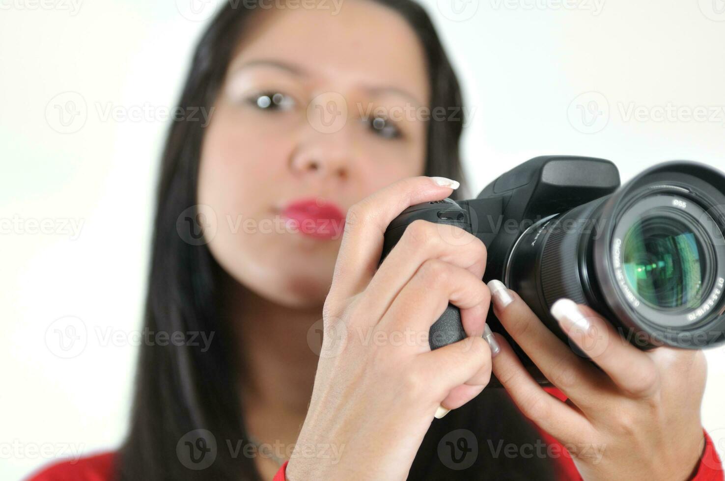 mujer joven sosteniendo una cámara en la mano tomando una foto aislada