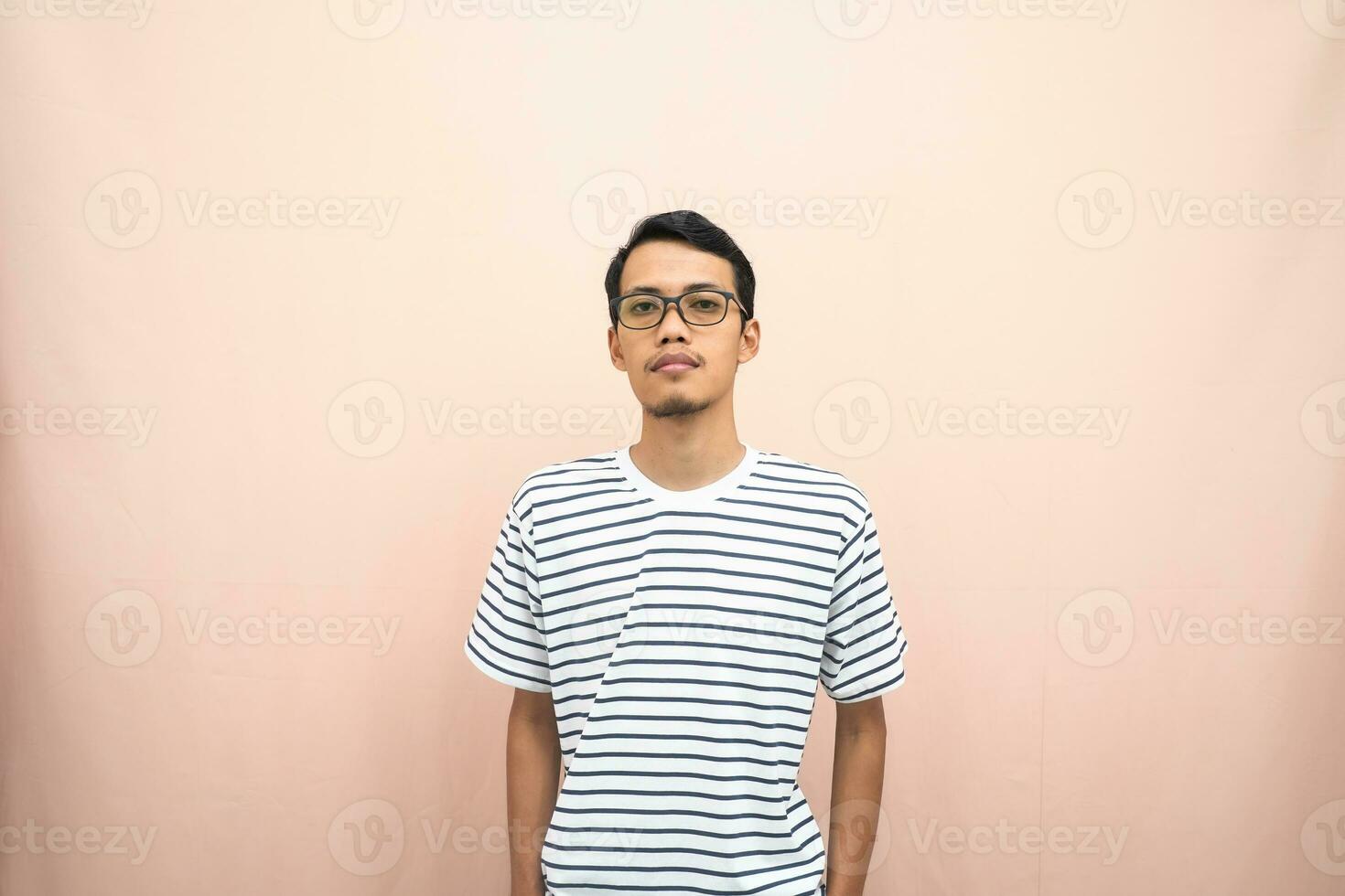 Asian man in glasses wearing casual striped t-shirt, standing pose, smiling and serious. photo