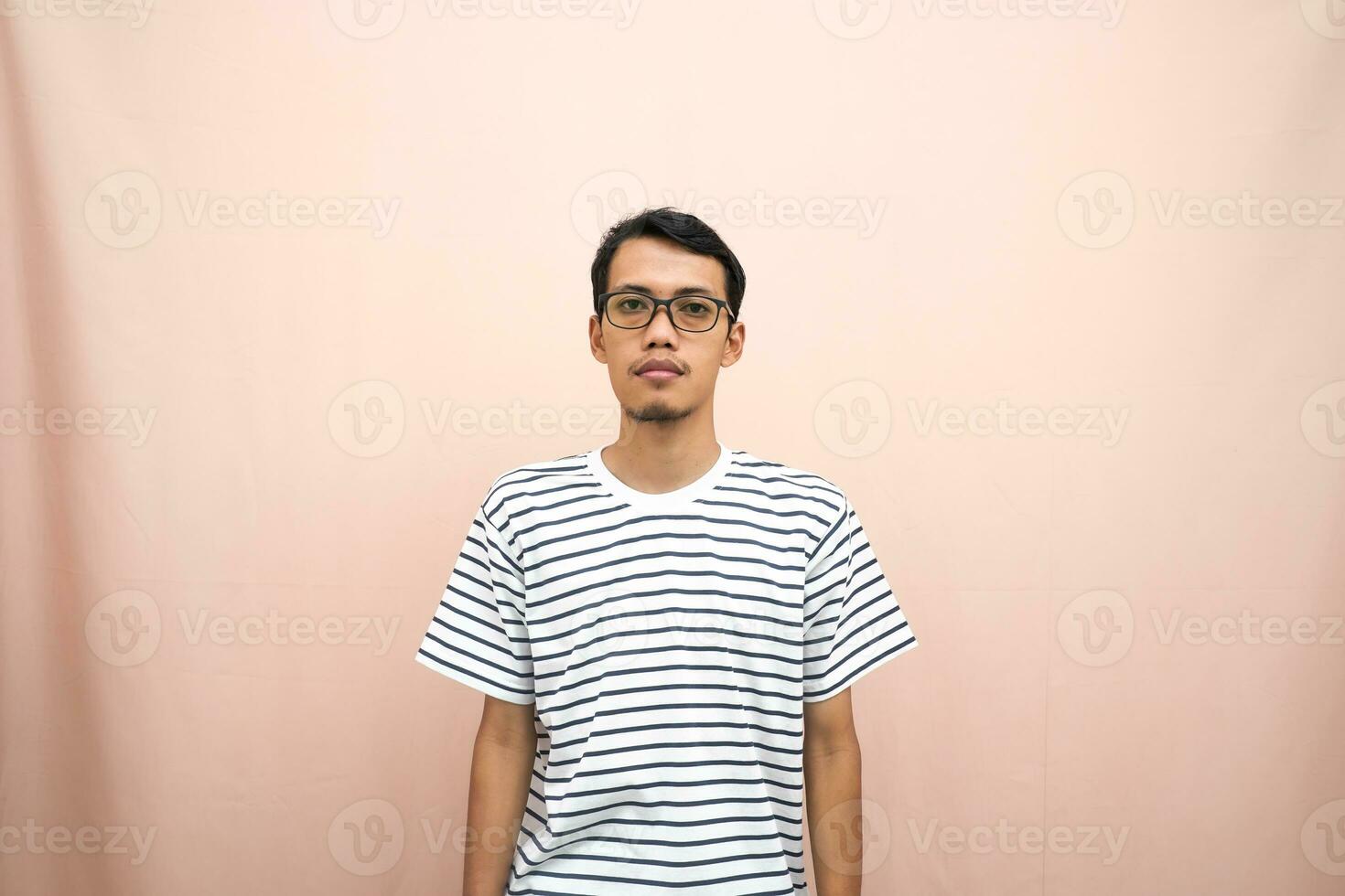 Asian man in glasses wearing casual striped t-shirt, standing pose, smiling and serious. photo