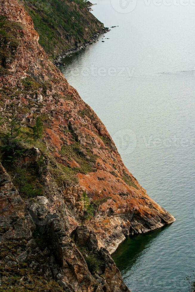Beautiful red rocks on the shore of Lake Baikal on Olkhon Island. Vertical frame. photo