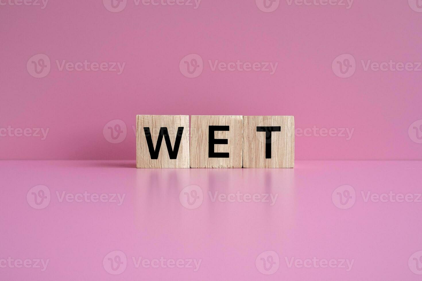 Wooden blocks form the text WET against a pink background. photo