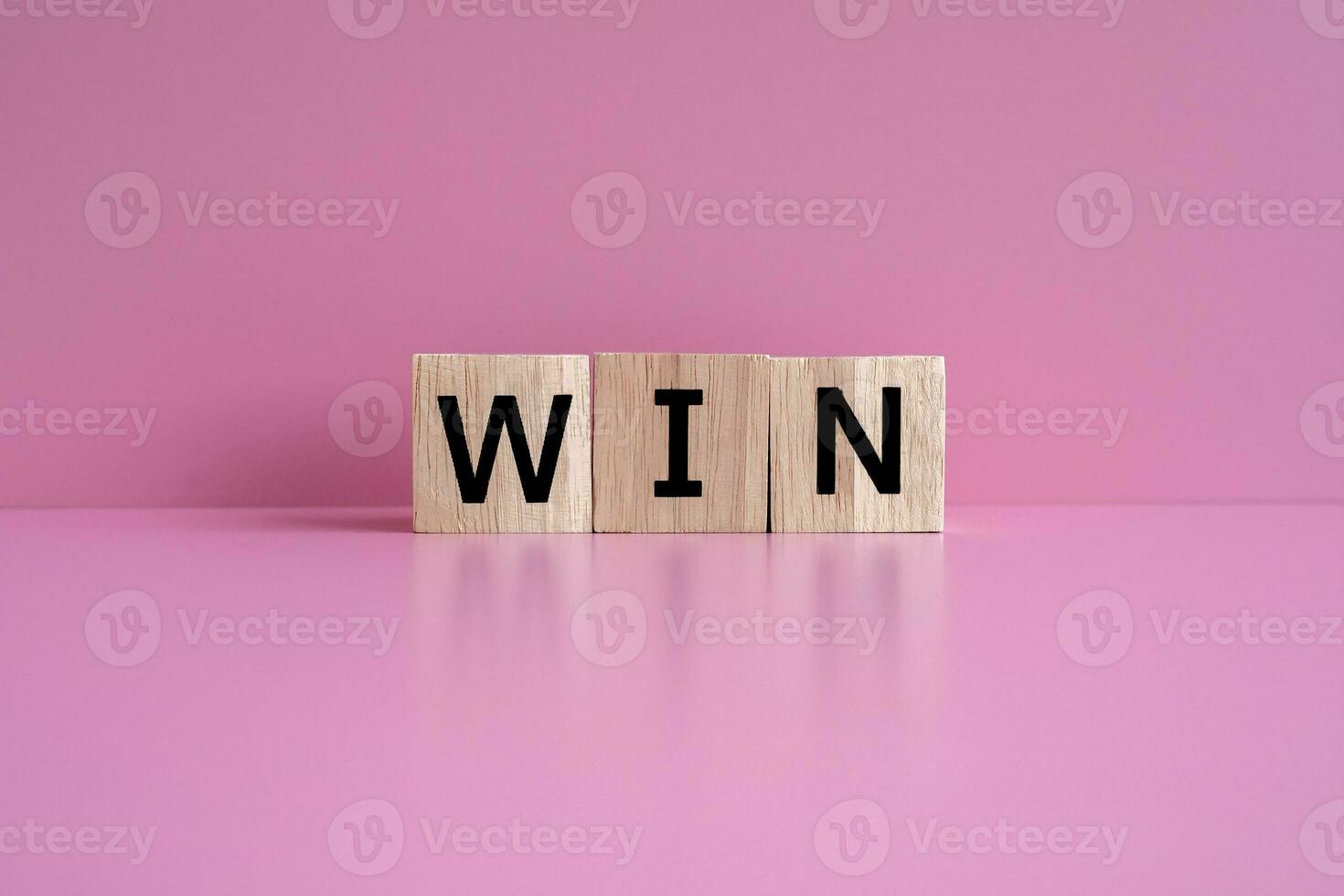 Wooden blocks form the text WIN against a pink background. photo