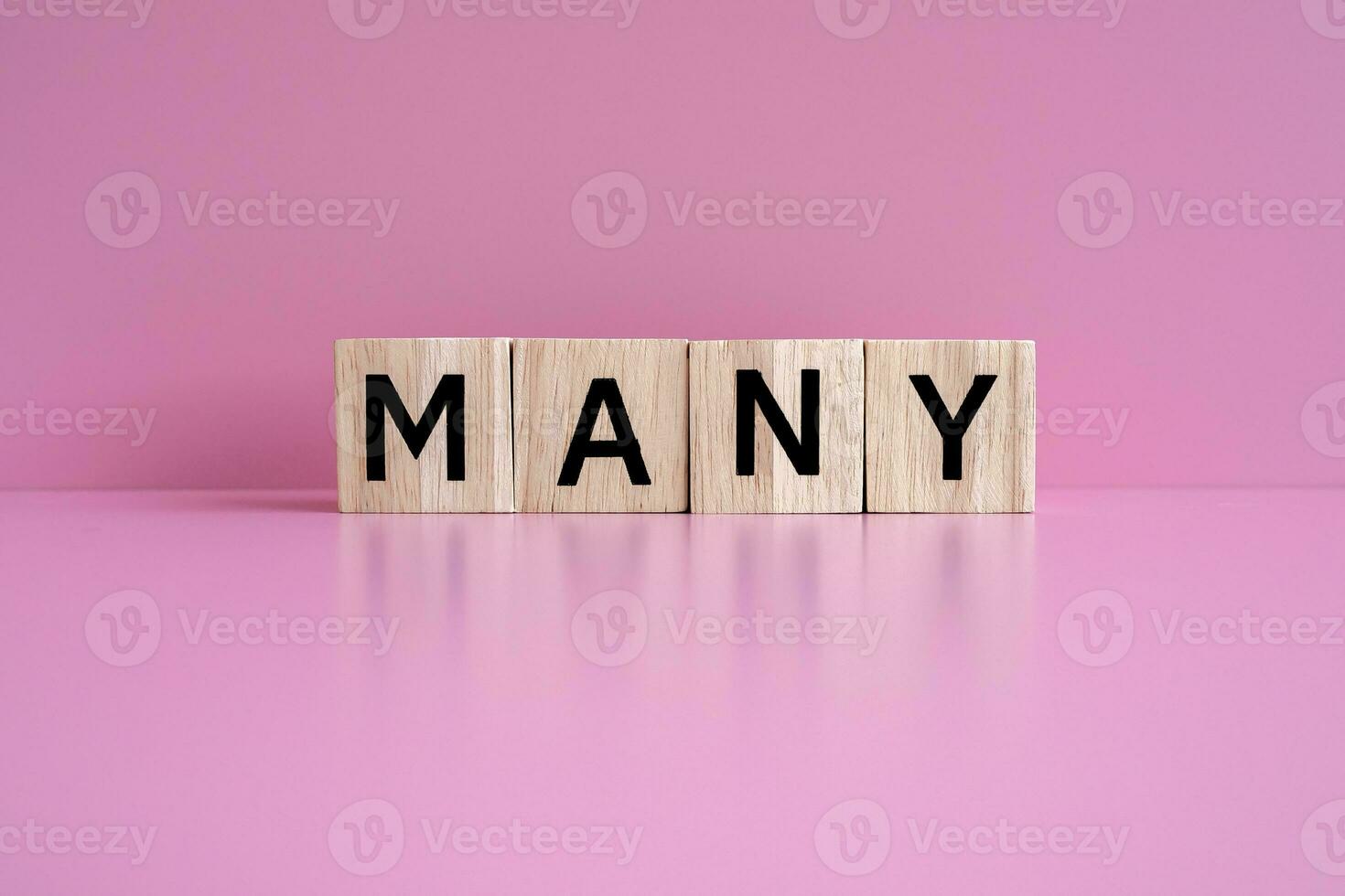 Wooden blocks form the text MANY against a pink background. photo