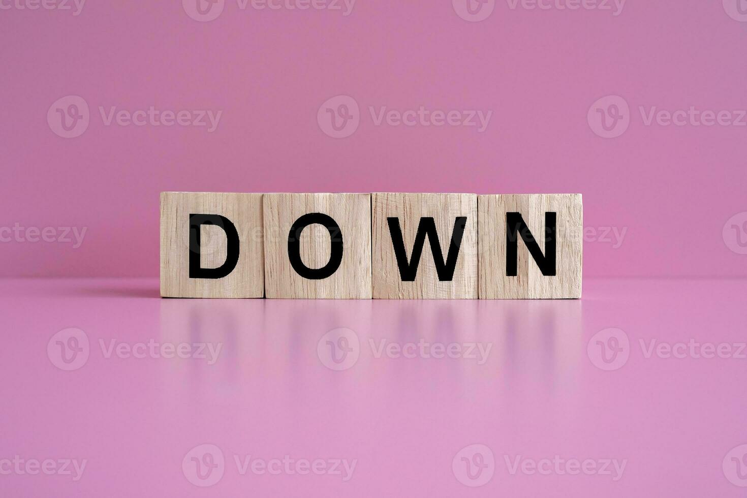 Wooden blocks form the text DOWN against a pink background. photo