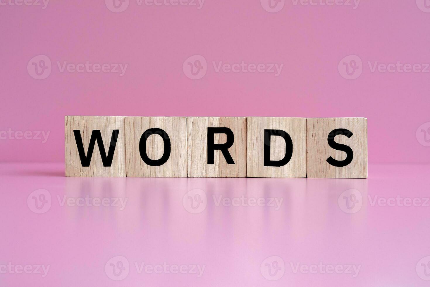 Wooden blocks form the text WORDS against a pink background. photo