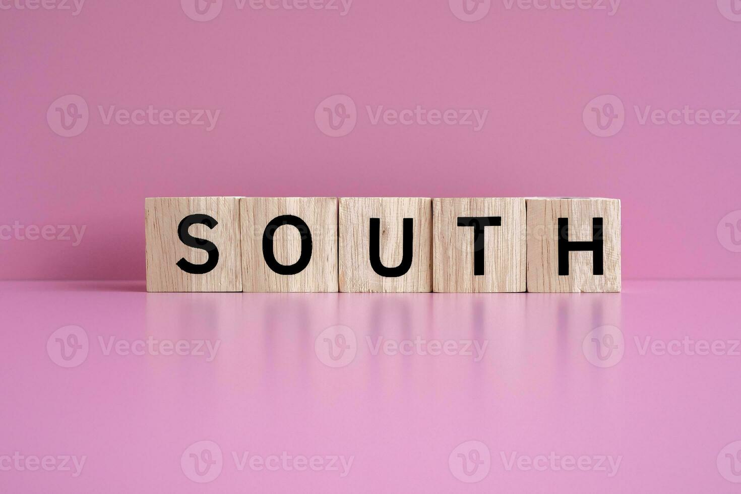 Wooden blocks form the text SOUTH against a pink background. photo