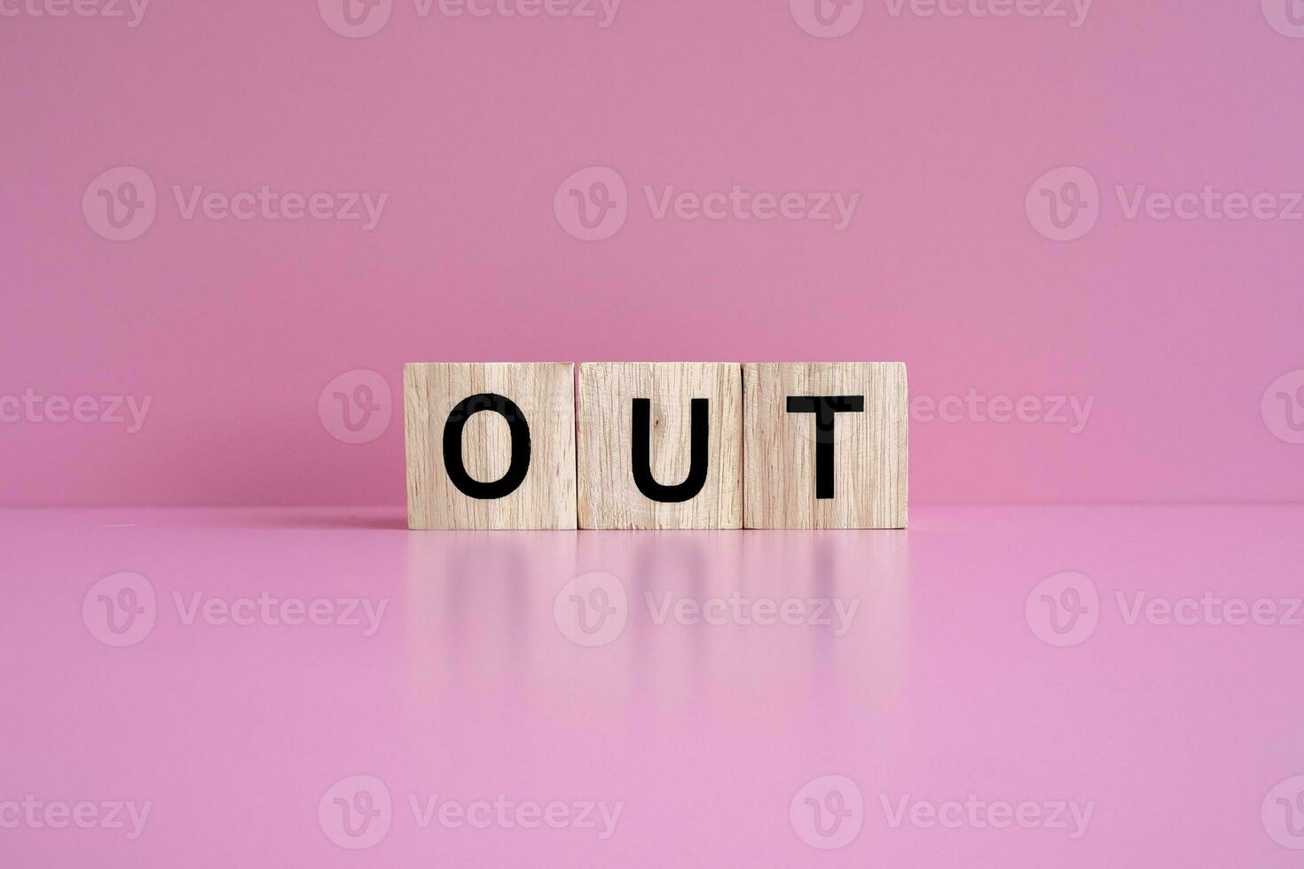 Wooden blocks form the text OUT against a pink background. photo