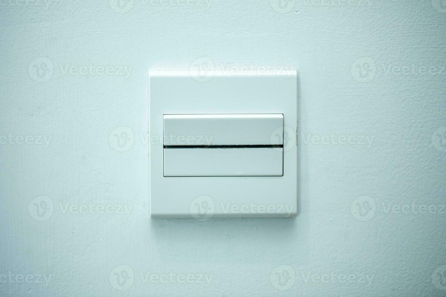 Long flat white on-off switch attached to white wall. White background. Close-up. photo