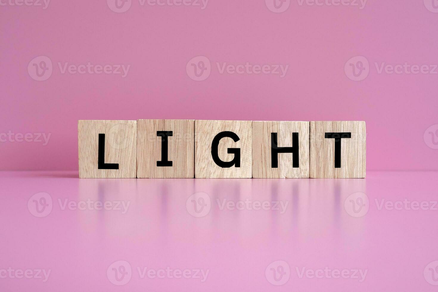 Wooden blocks form the text LIGHT against a pink background. photo