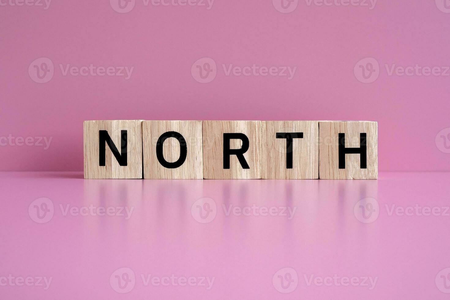 Wooden blocks form the text NORTH against a pink background. photo