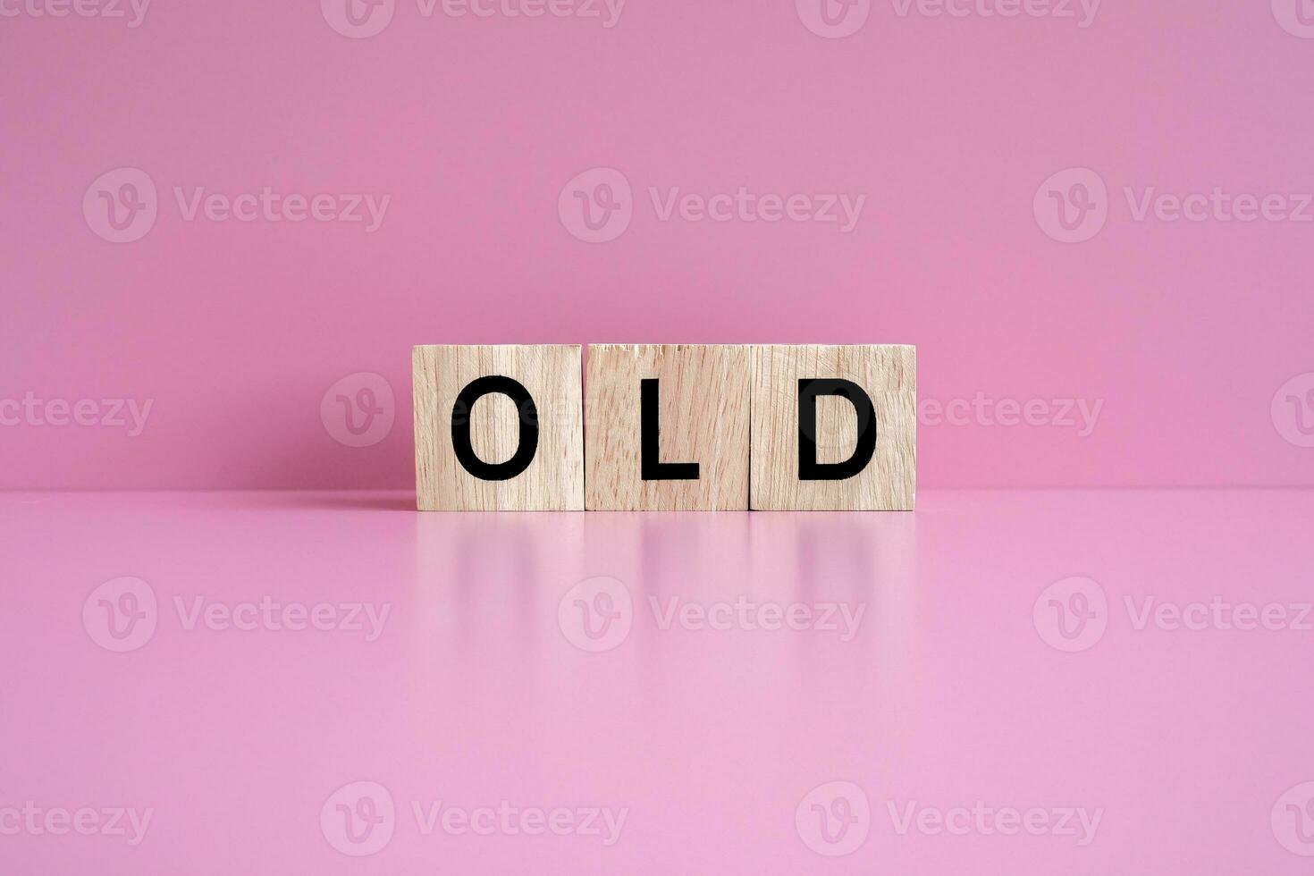 Wooden blocks form the text OLD against a pink background. photo