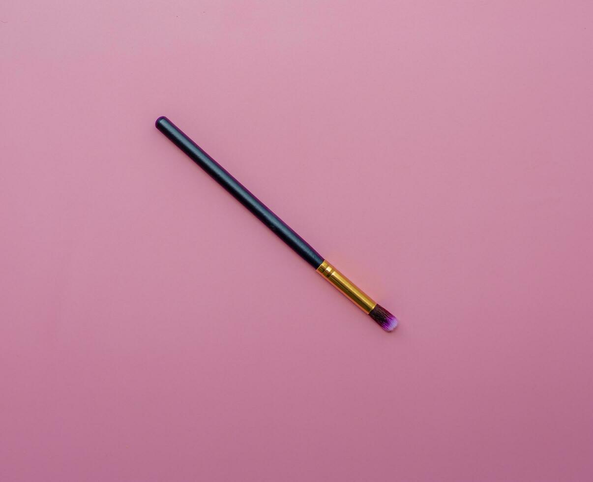 makeup brush on pink colored composed background. Top view photo