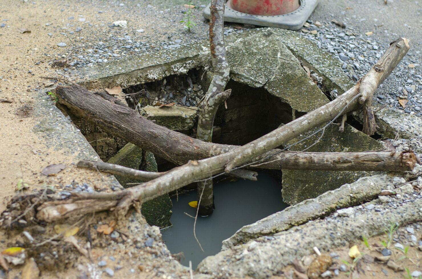 Damaged cement manhole covers broken on sidewalks and roads are a danger to users. Take the change of wood and cover it. photo