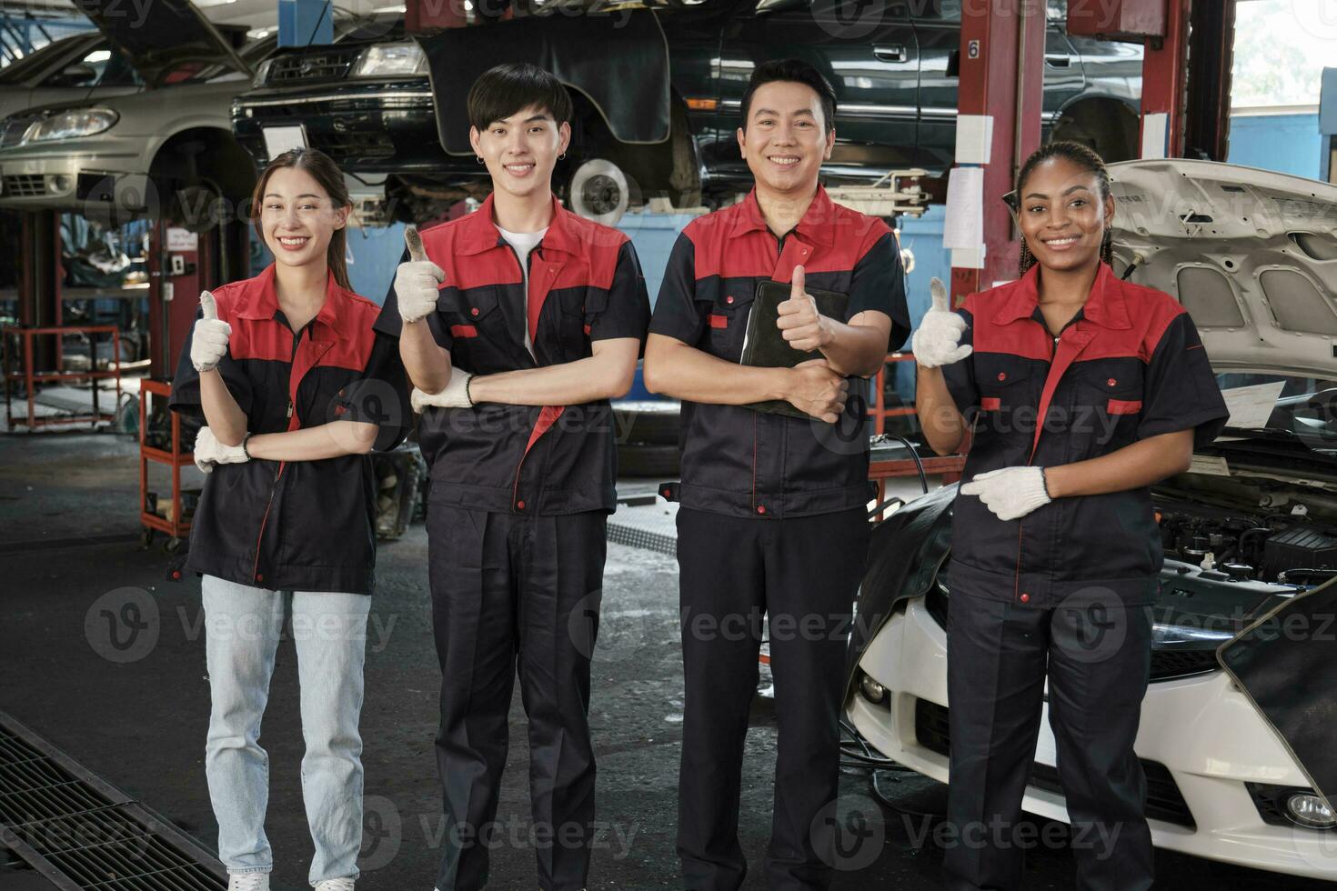 retrato de multirracial profesional mecánico equipo pulgares arriba y Mira a cámara, trabajo a coche Servicio cochera, contento mantenimiento trabajos, cheque y reparar ocupación en automotor industria negocio. foto