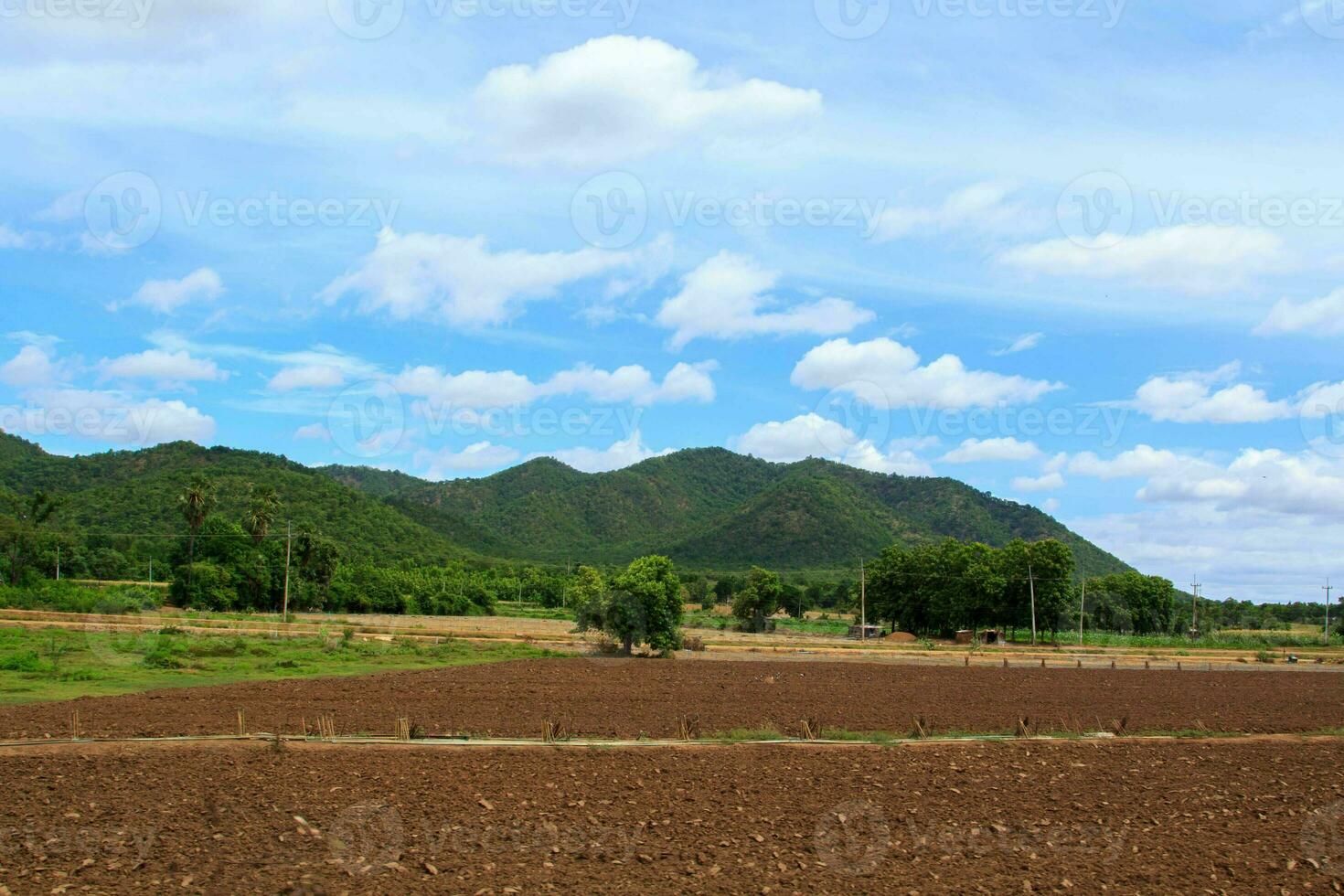 Farmers plow the soil with tractors to prepare the next season's crops and optimize the soil for cultivation in a setting with blue skies and mountains as a beautiful backdrop. photo