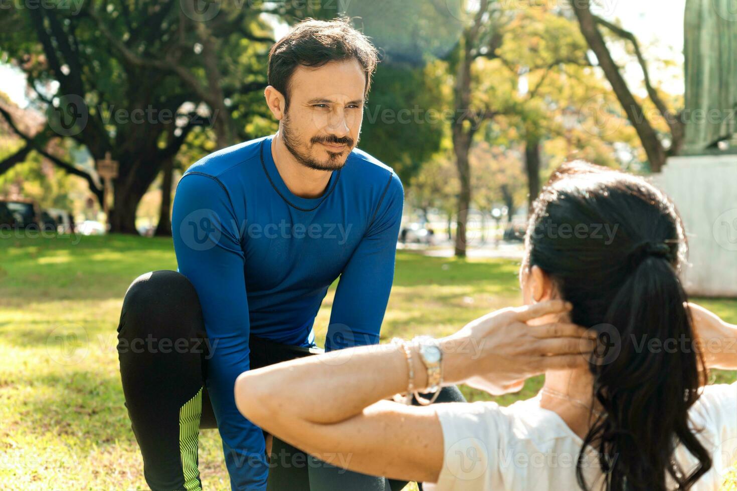 Male personal trainer training a woman outdoors. photo