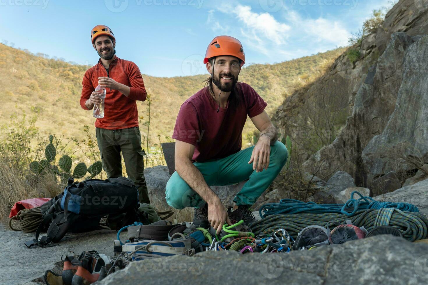 Smiling men preparing climbing gear. photo
