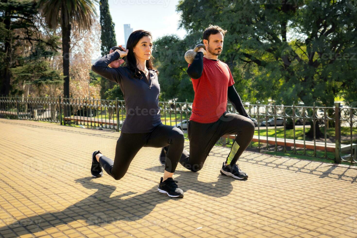 Man and woman training with weights in a city square. photo