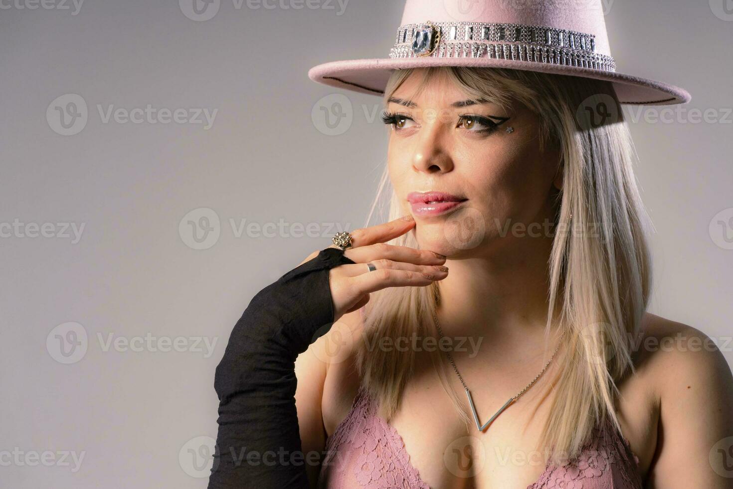 de cerca de sexy rubia mujer en rosado sombrero y lencería, vistiendo joyería y vistiendo negro guantes. foto